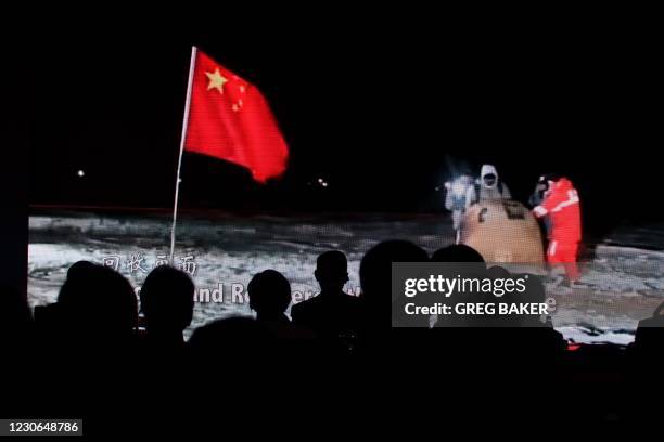 Audience members take photos of a screen showing a video about China's Chang'e-5 moon probe at an event announcing details of international access to...