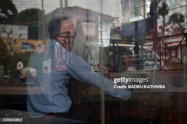 Man uses a computer to read news at a cyber cafe minutes after the Uganda Communication Commission, a body responsible for communications in Uganda,...