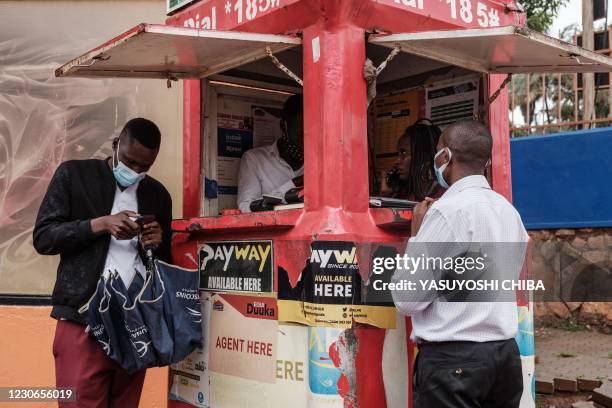 People wait at the mobile phone agent's kiosk in Kampala, Uganda, on January 18, 2021. - Internet was partially restored in Uganda on January 18,...