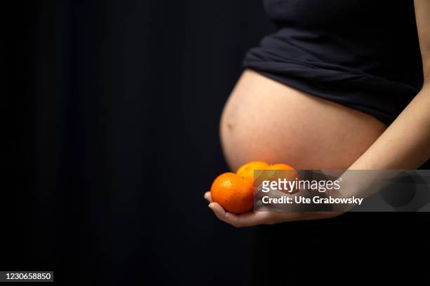 Bonn, Germany In this photo illustration a pregnant woman is showing her baby bump and some fruits on January 17, 2021 in Bonn, Germany.