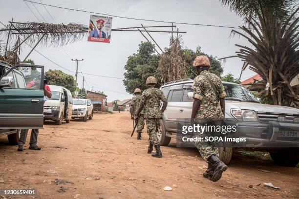 Soldiers walk towards the home of the opposition leader Bobi Wine whose real name is Robert Kyagulanyi, two days after Uganda's presidential...