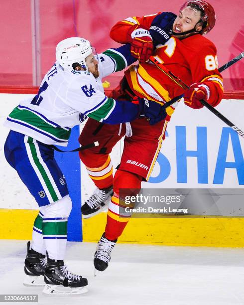 Nikita Nesterov of the Calgary Flames is checked by Tyler Motte of the Vancouver Canucks during an NHL game at Scotiabank Saddledome on January 18,...