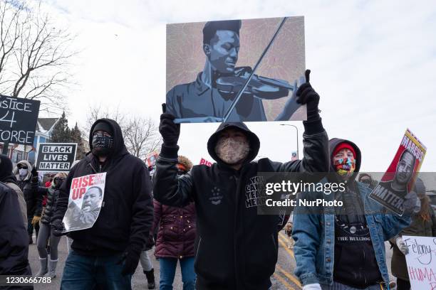 Protester holds a poster of Elijah McClain during a Martin Luther King Jr. Day march in St. Paul. January 18, 2021.