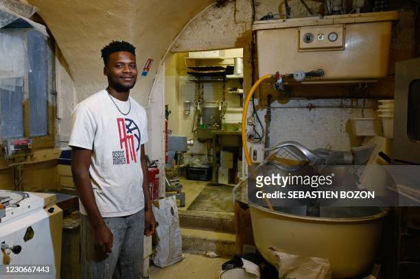 Guinean apprentice, Laye Fode Traore, poses in Stephane Ravacley's bakery, in Besancon, eastern France, on January 19, 2021. - French baker Stephane...