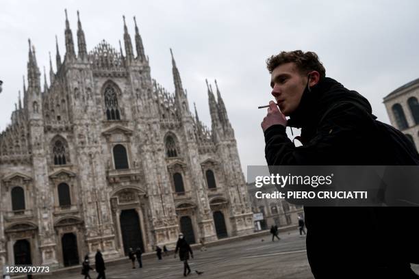 Man smokes a cigarette on Piazza del Duomo in Milan on January 19, 2021 as it became the first Italian city to introduce an outdoor smoking ban...