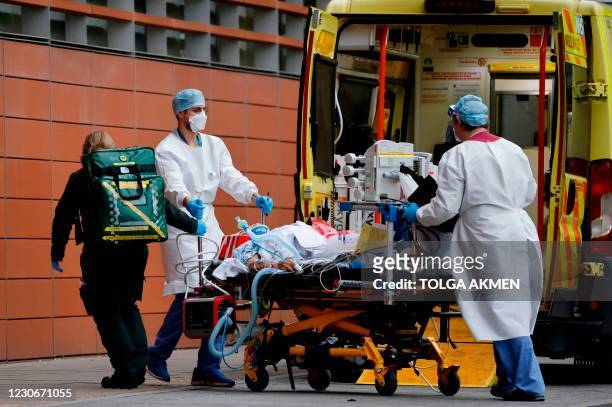 Medics take a patient from an ambulance into the Royal London hospital in London on January 19, 2021. - An estimated 12 percent of people in England...