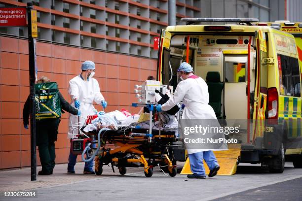 Paramedics wearing PPE wheel a patient from an ambulance outside the emergency department of the Royal London Hospital in London, England, on January...