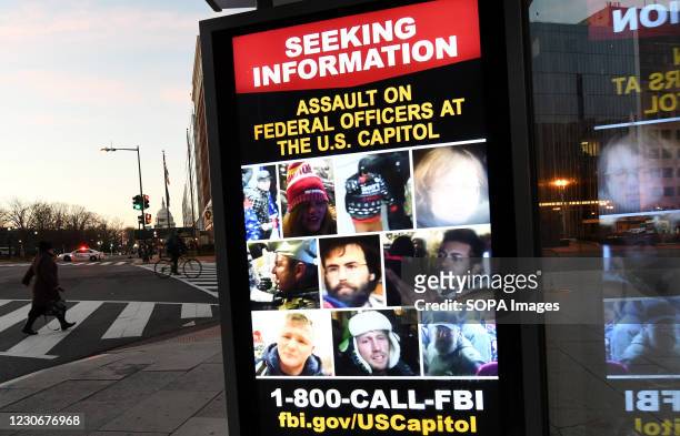 With the U.S. Capitol building seen in the background, a sign on a bus shelter asks the public for information about people involved in the Capitol...