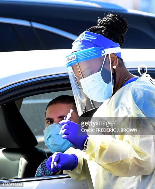 People pull up in their vehicles for Covid-19 vaccines in the parking lot of The Forum in Inglewood, California on January 19, 2021. - Five...