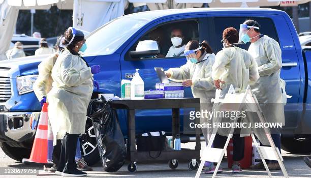 People pull up in their vehicles for Covid-19 vaccines in the parking lot of The Forum in Inglewood, California on January 19, 2021. - Five...