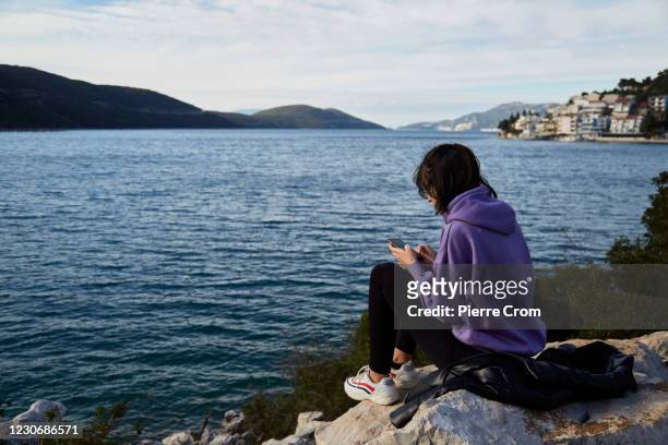 Iva, a Bosnian Croat resident who study economy in Zagreb, Croatia, eyes her smartphone on the Adriatic Sea near the border with Croatia on January...