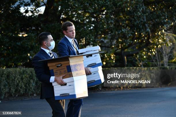 Aids carry boxes to Marine One before outgoing US President Donald Trump departs the White House in Washington, DC, on January 20, 2021. - President...