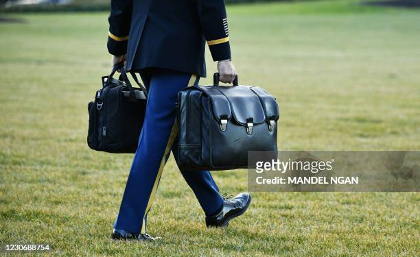 Military aide carries the nuclear "football" with the equipment and nuclear codes to Marine One after US President Donald Trump and First Lady...