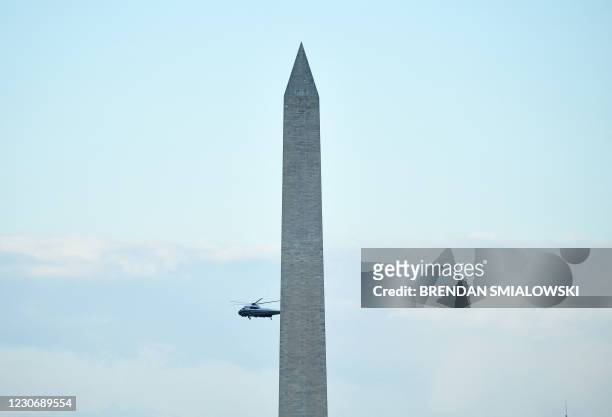 Marine One with US President Donald Trump and First Lady Melania Trump flies past the Washington Monument as it departs the White House in...