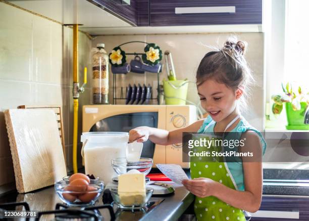 meisje dat een cake van recept maakt - baking reading recipe stockfoto's en -beelden