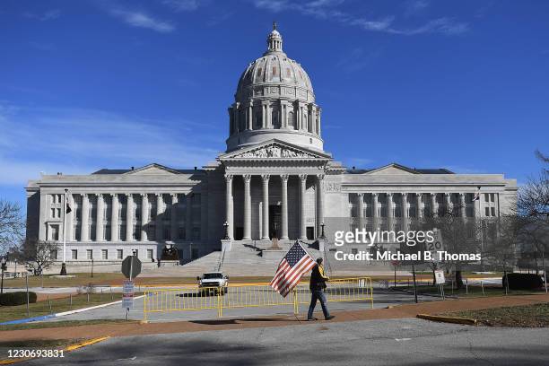 Man waves and American flag as he walks outside the Missouri State Capitol building on January 20, 2021 in Jefferson City, Missouri. Supporters of...