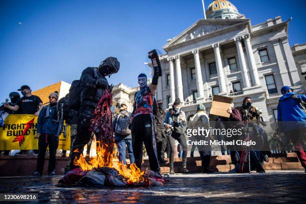 Members of the Communist Party USA and other anti-fascist groups burn an American flag on the steps of the Colorado State Capitol on January 20, 2021...