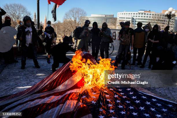 Members of the Communist Party USA and other anti-fascist groups burn an American flag on the steps of the Colorado State Capitol on January 20, 2021...