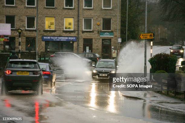 Car seen splashing water as it moves on a waterlogged street during a heavy rainfall in Holmfirth. Parts of the UK including South Yorkshire and...