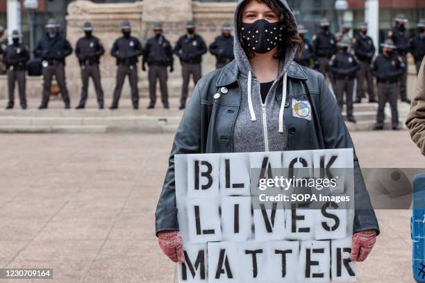 Woman holds a Black Lives Matter sign in front of a line of Ohio State Troopers in from of the Ohio Statehouse. Activist groups in Columbus came...