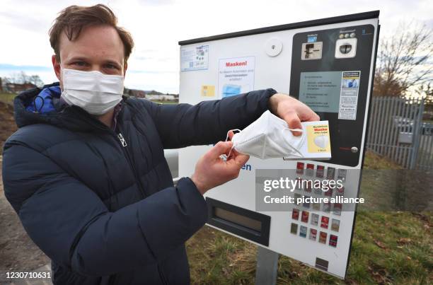 January 2021, Bavaria, Gerolzhofen: Menas Wolf, managing director of Wolf Tabakwaren e.k., holds an FFP2 mask with packaging in front of one of his...