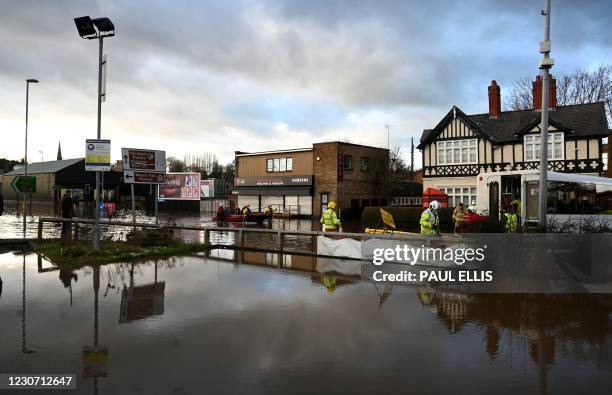 Members of the Emergency Services, wearing face mask coverings due to the COVID-19 pandemic, wade through flood water as they work to evacuate people...