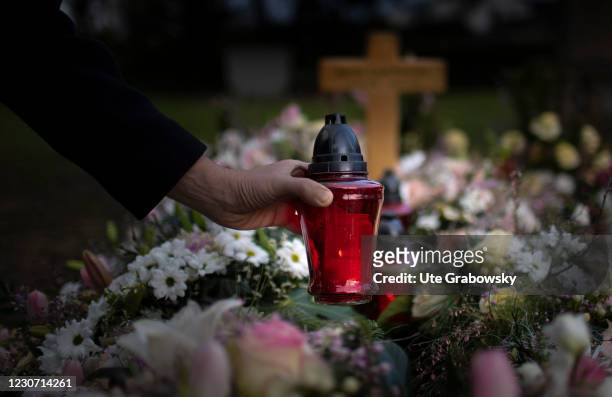 In this photo illustration a man puts a grave light on a grave on January 21, 2021 in Bonn, Germany.