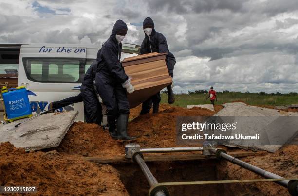 Workers of a funeral palour dressed in protective clothing carry a coffin of a Covid-19 victim to the grave at a memorial park on January 21, 2021 in...