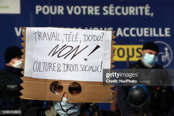 Musician plays accordion while wearing a placard reading 'Work, TV, sleep ? NO ! Culture and social rights !' in front of riot policemen guarding the...