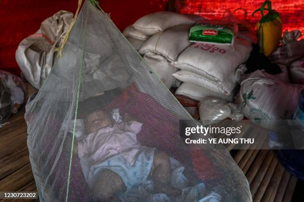 This photo taken on January 11, 2021 shows a Chin baby sleeping under a mosquito net in Bethel village in Hmawbi, on the outskirts of Yangon, where...