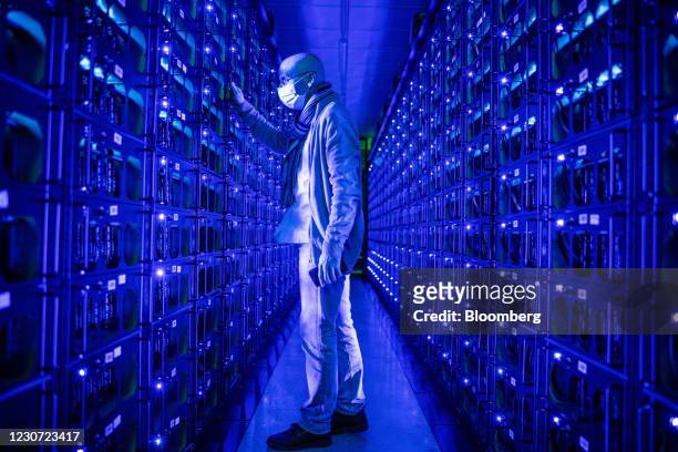 An employee wearing a protective face mask inspects mining rigs mining the Ethereum and Zilliqa cryptocurrencies at the Evobits crypto farm in...
