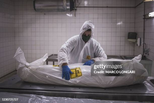 Morgue attendant at the Pretoria branch of the South African funeral and burial services company Avbob applies a biohazard warning on the body of a...