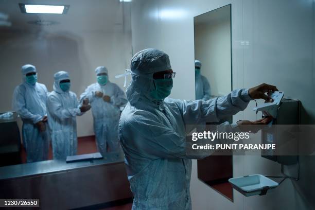 Employees prepare themselves before getting inside a lab where Covishield, AstraZeneca-Oxford's Covid-19 coronavirus vaccine is being manufactured,...