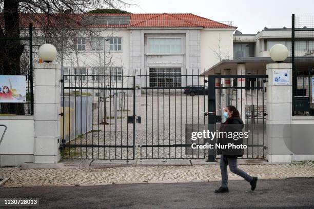 Woman wearing a face mask walks by the Sebastiao e Silva closed school in Oeiras, near Lisbon on January 22, 2021. Portugal applied more tightened...