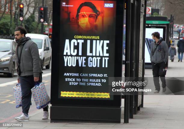 Man walks next to an 'Act Like You've got it' warning sign on a London street. England remains under lockdown as the Prime Minster Boris Johnson...
