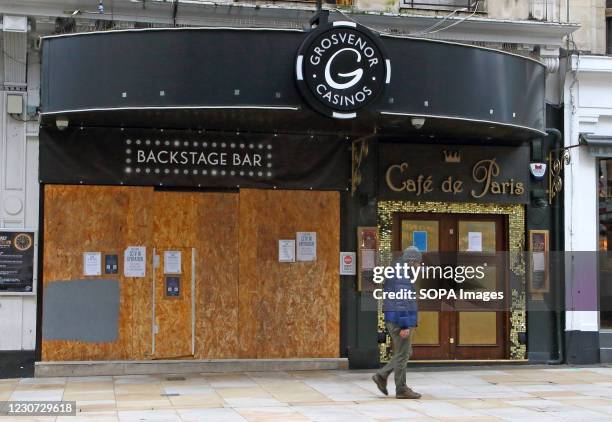 Man walks past a closed and boarded up Cafe de Paris. England remains under lockdown as the Prime Minster Boris Johnson refuses to rule out that it...