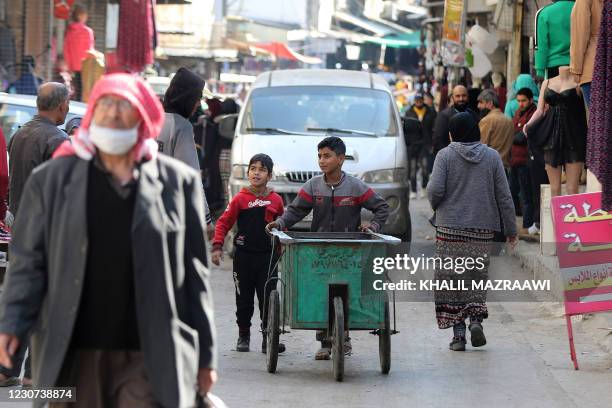 Jordanian youths use a hand cart to work in Amman's Wahdat district on January 10, 2021. - Many minors have been forced prematurely into the labour...