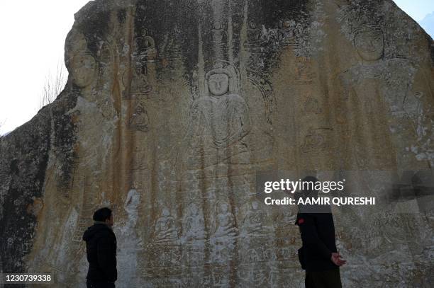 In this picture taken on January 22 visitors look at a large granite rock on which pictures of Buddha have been engraved -- between the 8th and 10th...