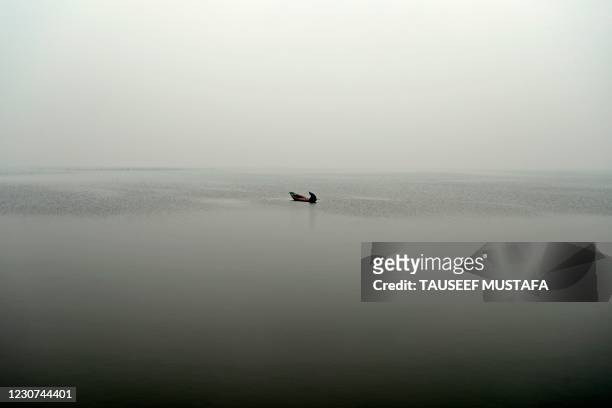 Fisherman rows a boat in Dal Lake during snowfall in Srinagar on January 23, 2021.