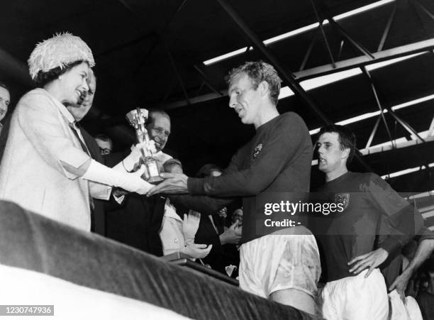 Britain's Queen Elizabeth of England presents the Jules Rimet Cup to Bobby Moore, captain of England's national soccer team, as her husband Prince...