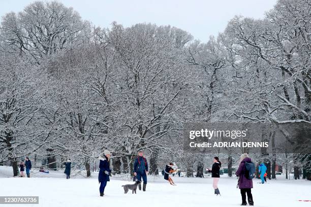 Steve and Emma Bartlett watch as their dog "Ruby" jumps to catch a snowball on a snow-covered common in Hartley Wintney west of London on January 24,...