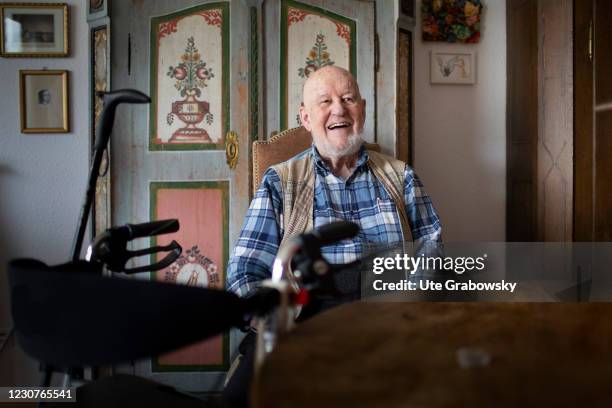 Heidelberg, Germany In this photo illustration an old man, sitting at his livingroom table is laughing on January 23, 2021 in Heidelberg, Germany.