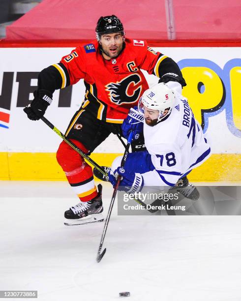 Mark Giordano of the Calgary Flames checks T.J. Brodie of the Toronto Maple Leafs during an NHL game at Scotiabank Saddledome on January 24, 2021 in...
