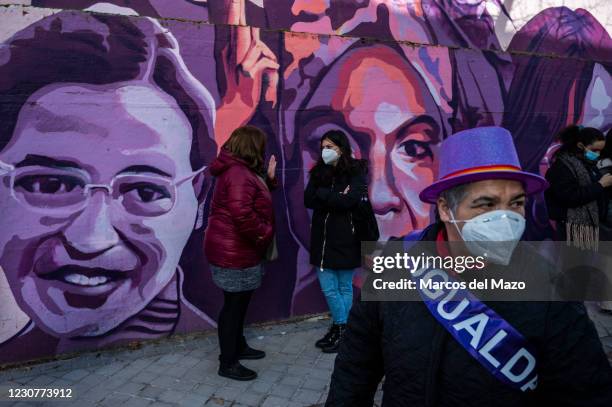 Woman wearing a ribbon with the word 'equality' passing by a feminist mural named 'Union makes force', during a protest against the removal of the...