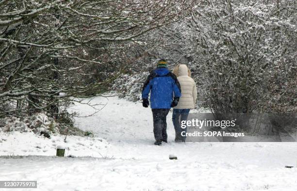 Couple walk along a path covered by snow blocks during the snowfall. With severe weather warnings issued across the UK including the south and east...