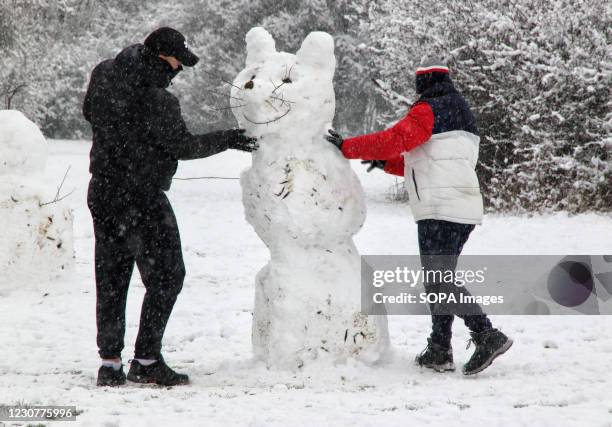 Couple seen making final touches to a snowman during the snowfall. With severe weather warnings issued across the UK including the south and east of...