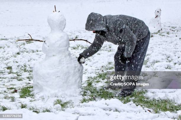 Man seen making final touches to a snowman in his garden during the snowfall. With severe weather warnings issued across the UK including the south...