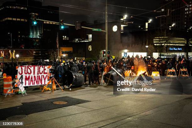 Barricade, with a banner referencing the 2020 death of Manuel Ellis in police custody, burns in an intersection in downtown Tacoma during an...