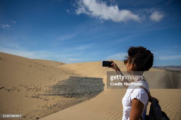 Tourist takes a picture landscape of the sand dunes of Maspalomas with her phone on the island of Gran Canaria, Spain on January 23, 2021.