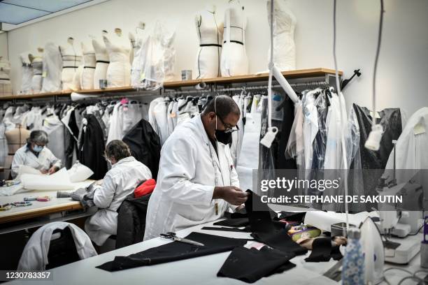 Employees work on a couture garment at Christian Dior's fashion house workshop in Paris on January 20, 2021. - With no catwalk fashion shows on...
